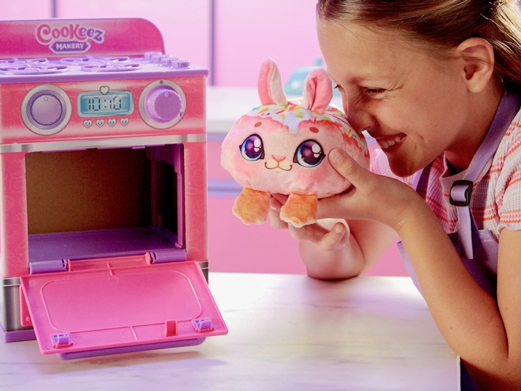 someone holding a plush of a baked bunny next to a toy oven