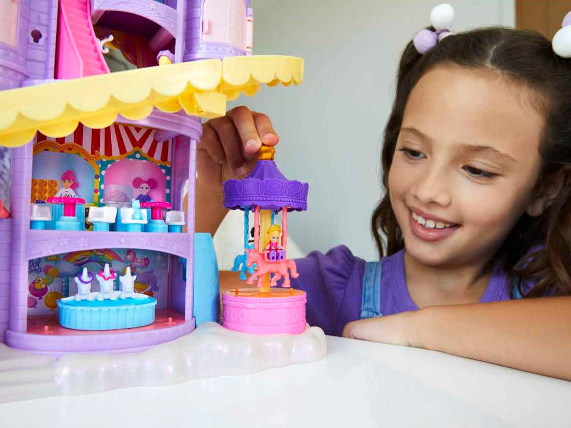 a little girl playing with a polly pocket funland theme park playset