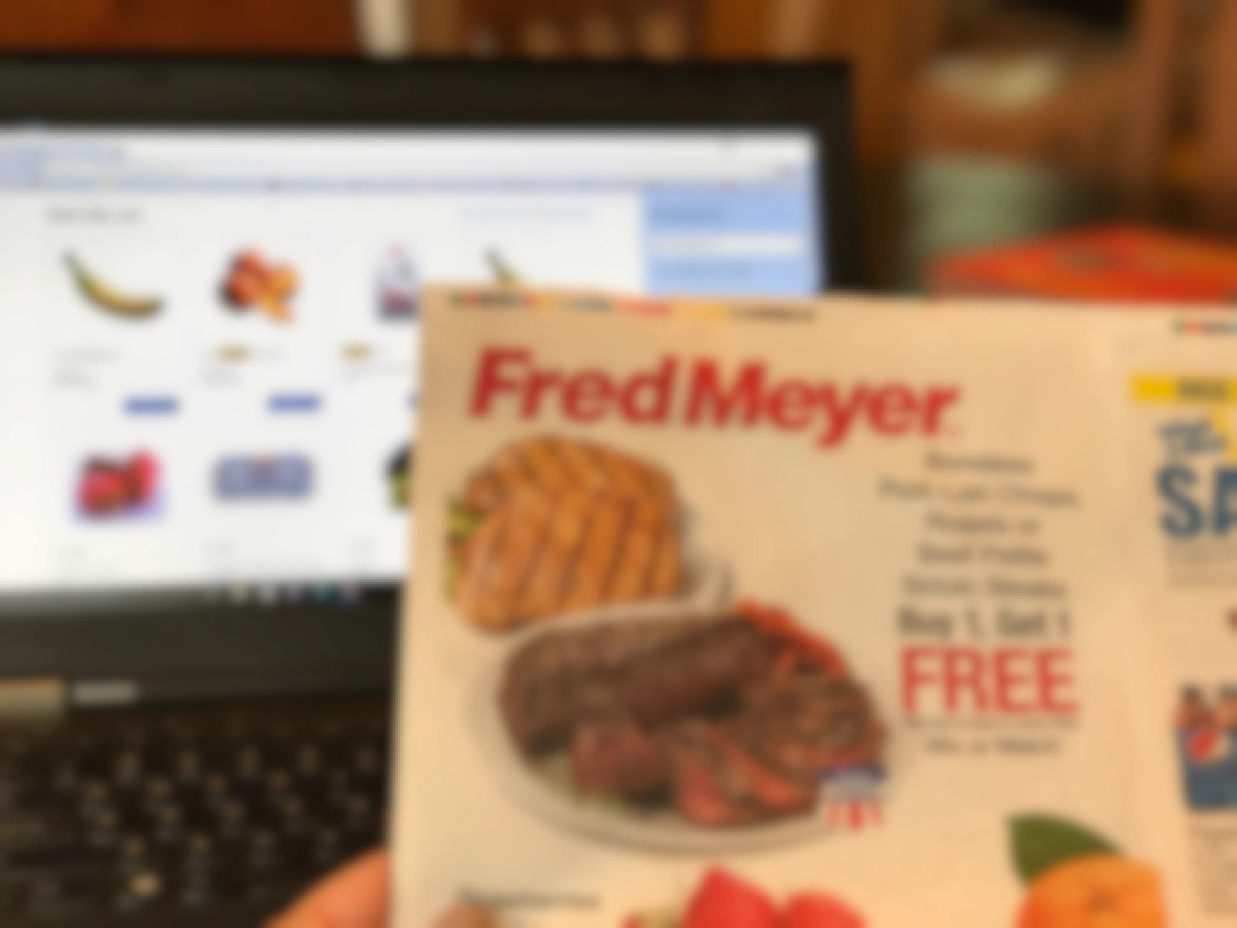 hand holds up fred meyer ad to fred meyer online grocery site