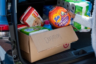 A woman putting a container of Tide Pods into a box in the trunk of a car