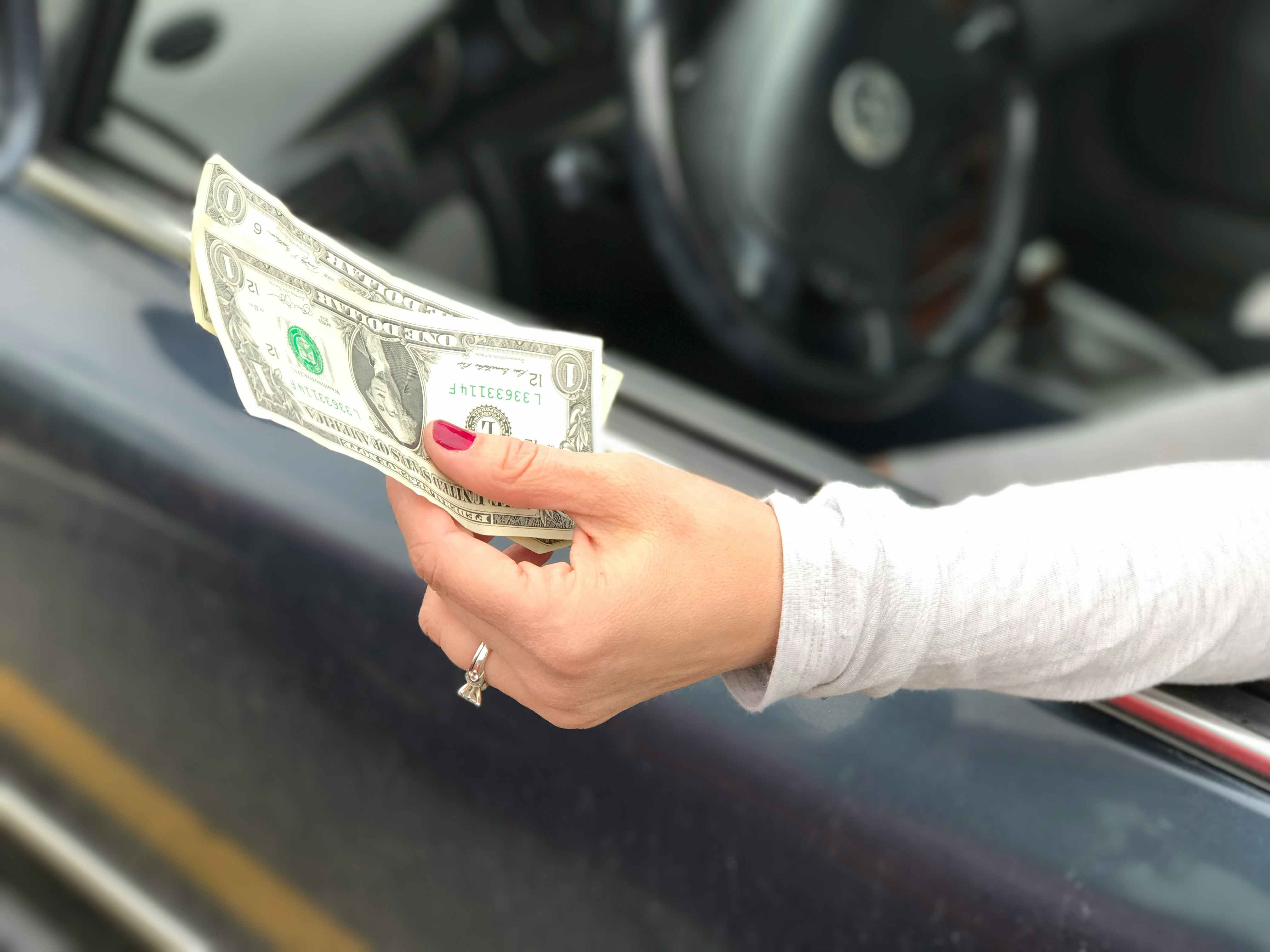 Person holding cash outside a car door