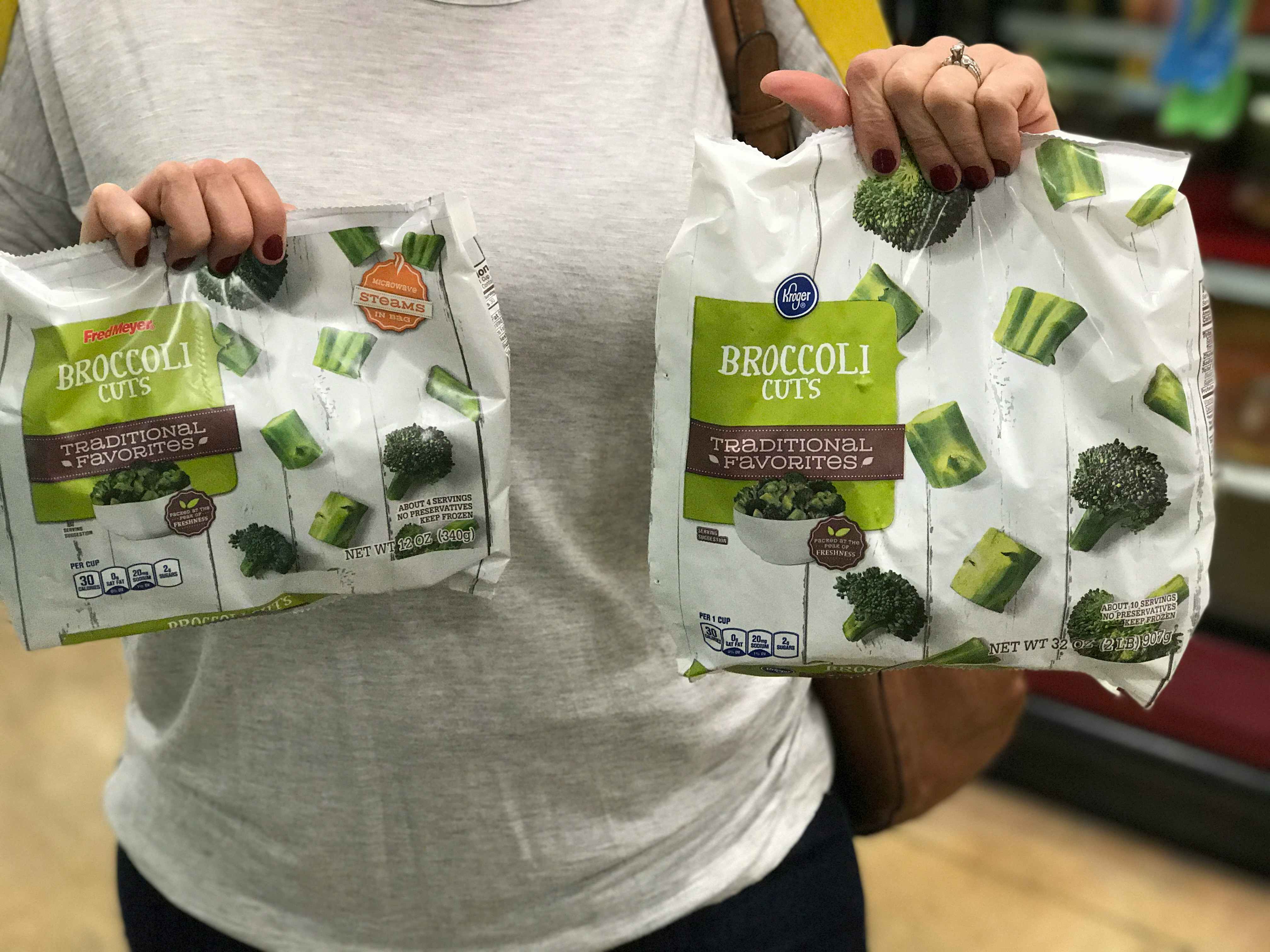 person holding two bags of broccoli