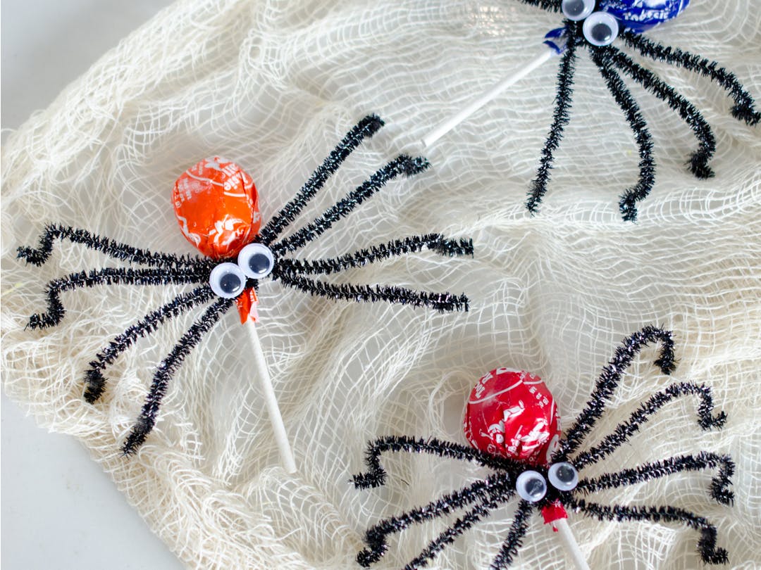 three spiders made out of tootsie pops, pipe cleaners, and googly eyes