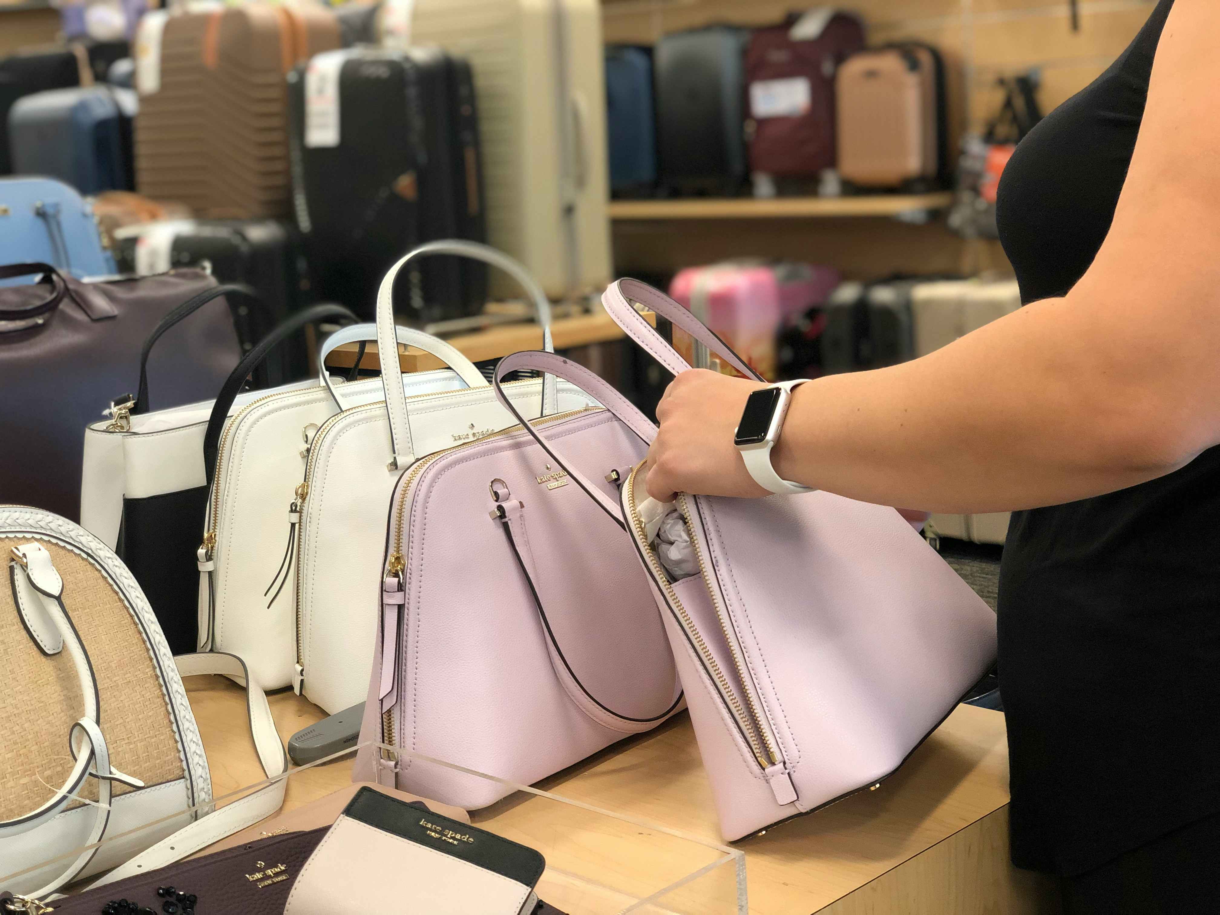 hand sorts through kate spade bags at the outlet