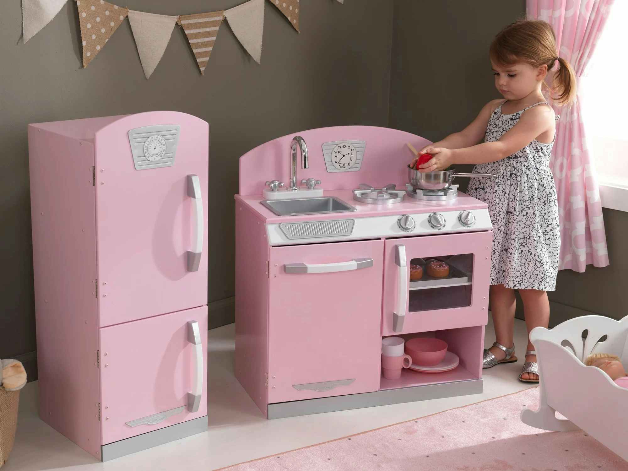 a little girl playing with a kidcraft retro kitchen