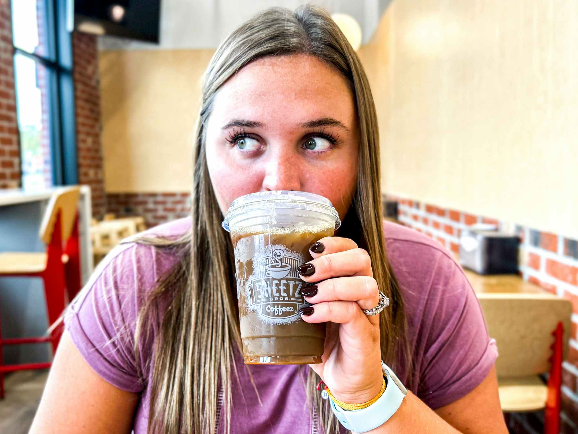 a person taking a drink out of a sheetz coffee