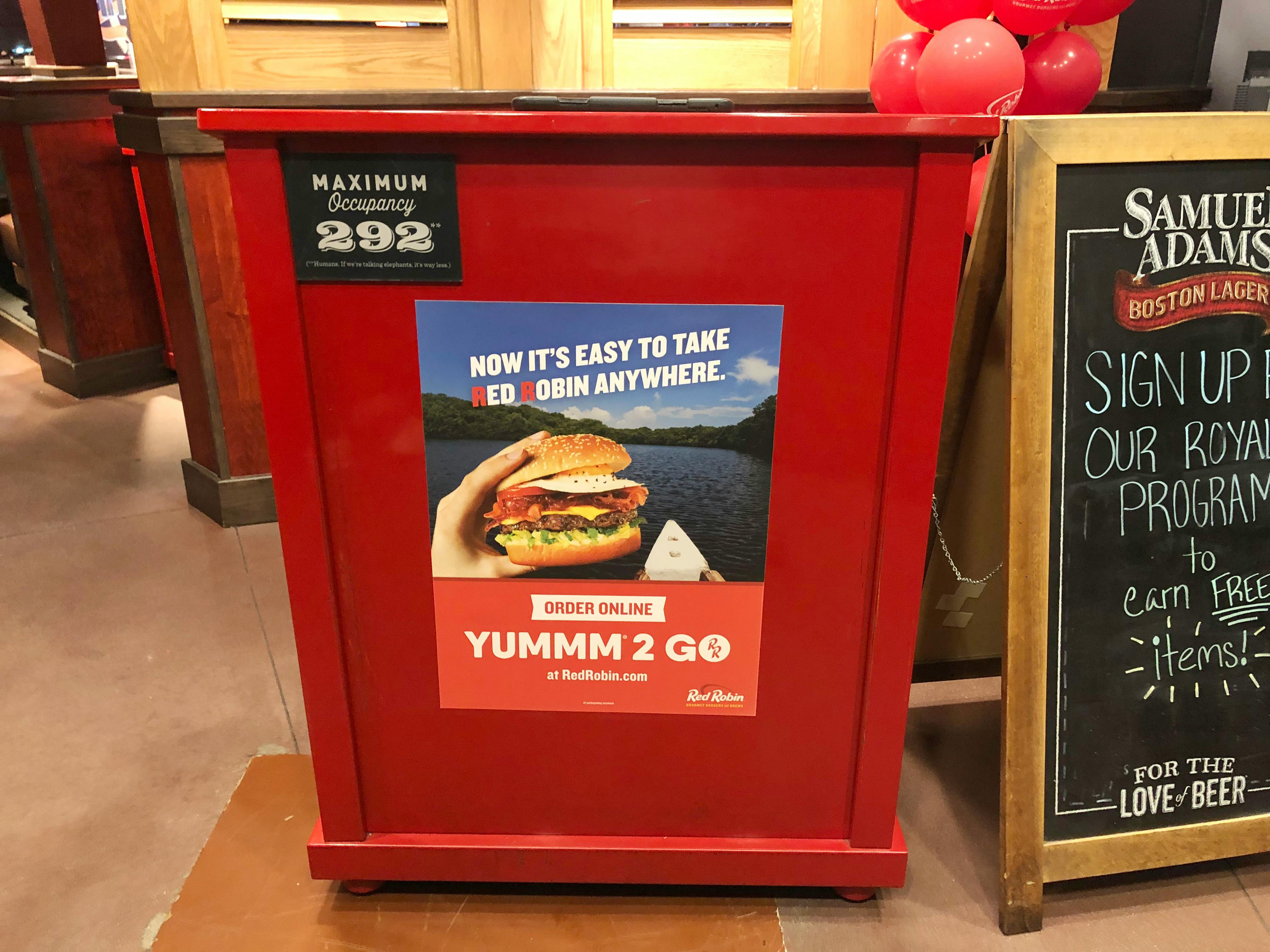 A Red Robin host podium inside of Red Robin next to a chalkboard advertising the Royalty Rewards program.
