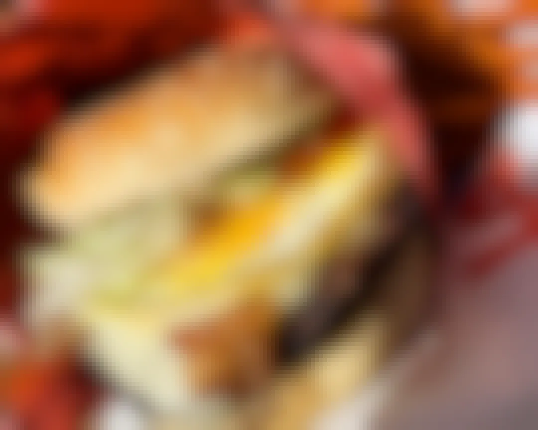 A close-up of a Red Robin burger with bacon and an egg on it, sitting in a basket with fries.