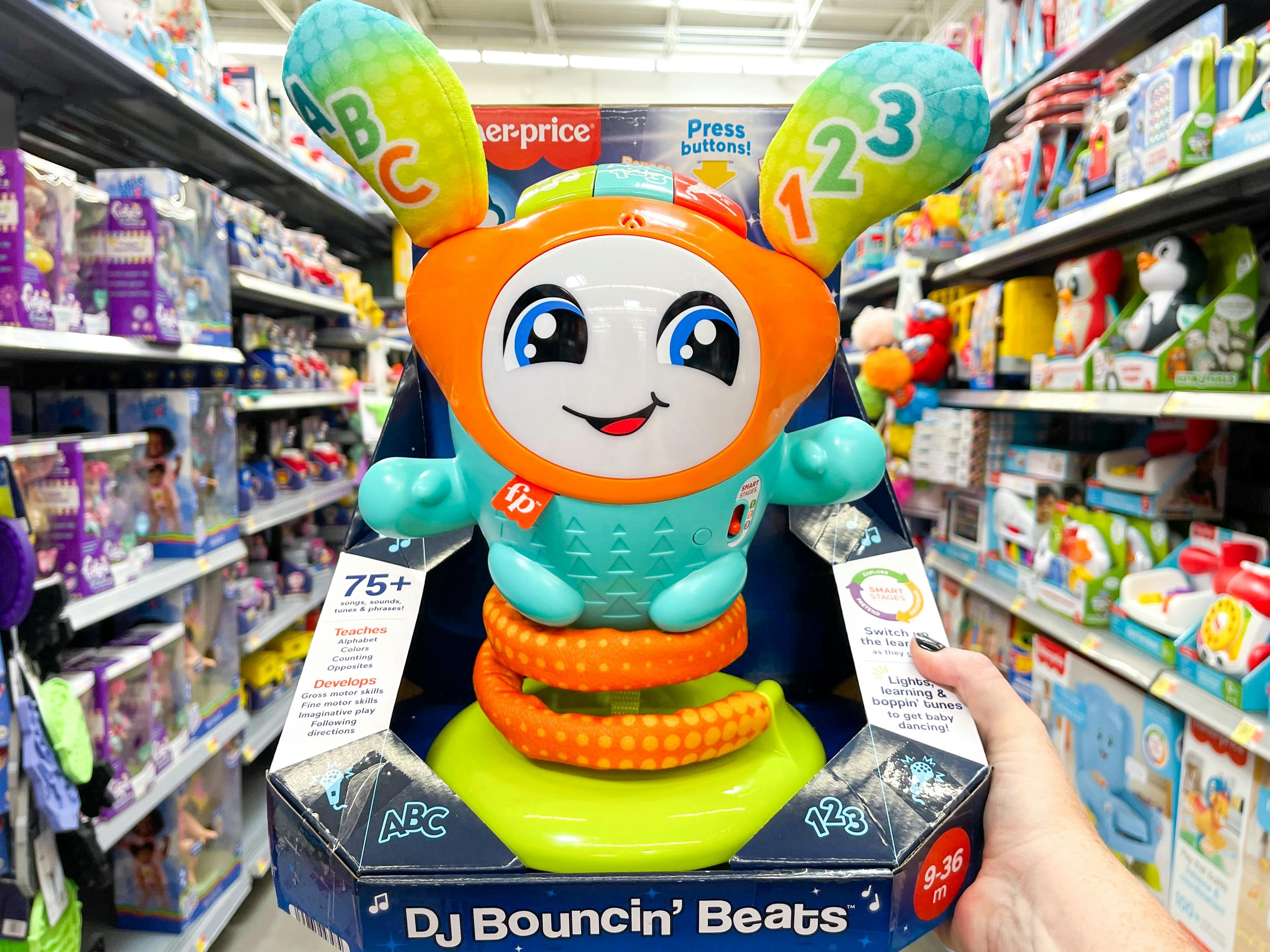 A person holding up a Fisher-Price DJ Bouncing Beats Interactive Baby and Toddler Toy in the toy aisle.