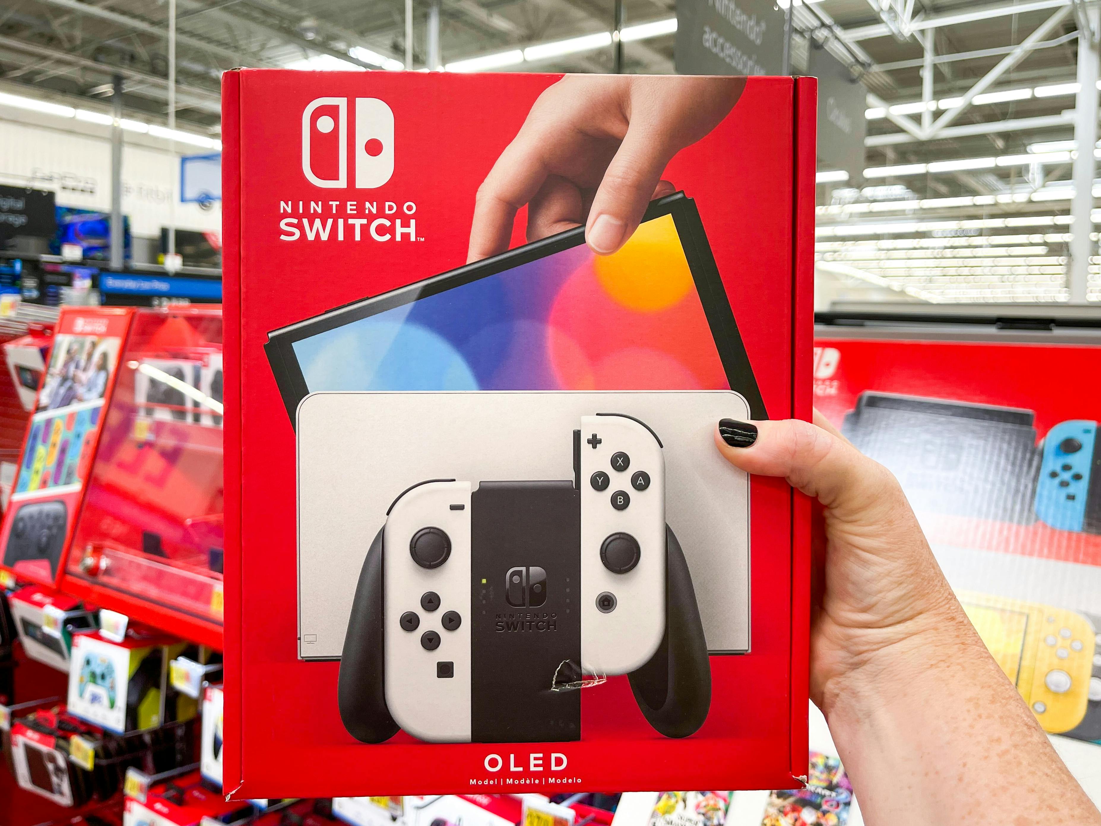 A person holding up a Nintendo Switch OLED in the Nintendo video game aisle.