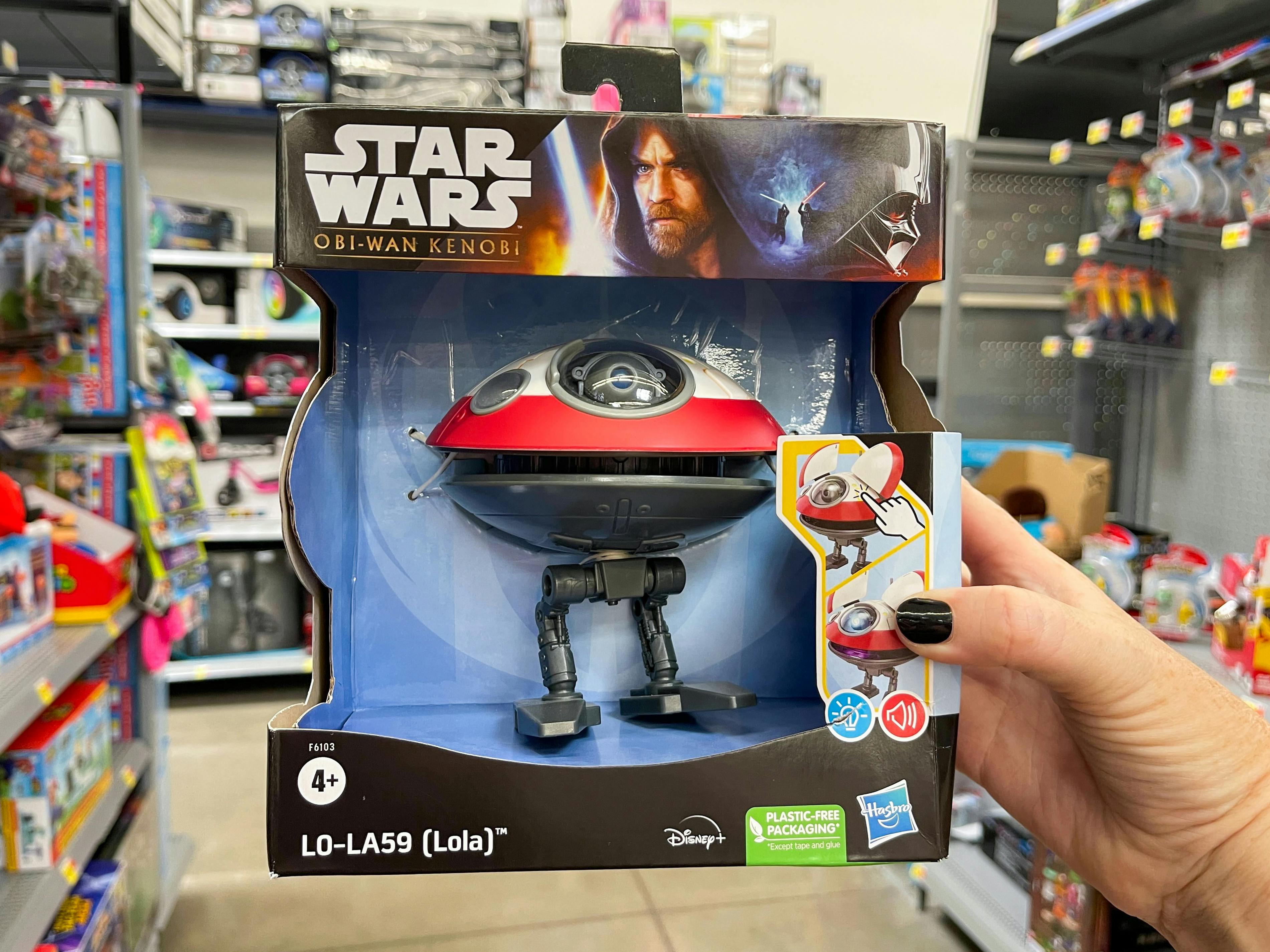 A person's hand holding a Star Wars Lola Droid toy in the toy aisle.