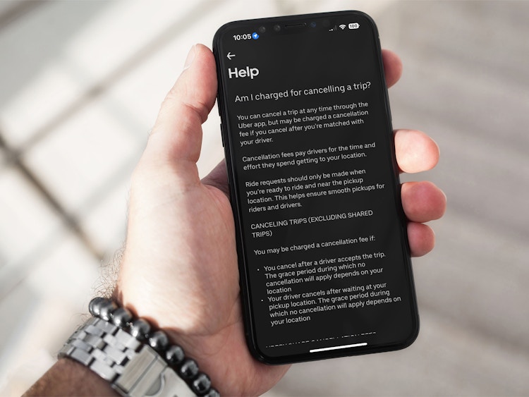 someone holding a phone displaying the Uber cancellation fees policy