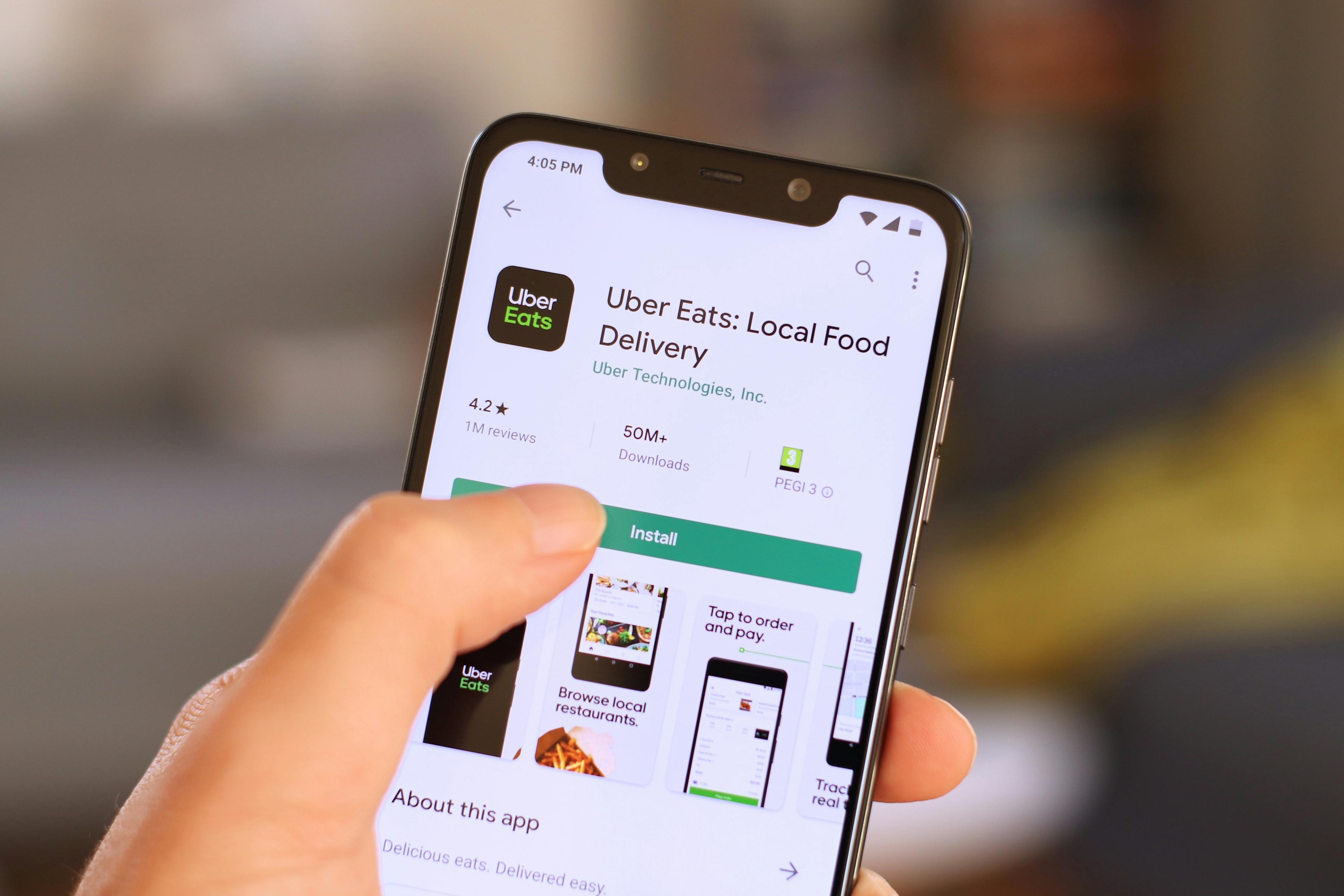 A person downloading the Uber Eats app onto their cell phone.