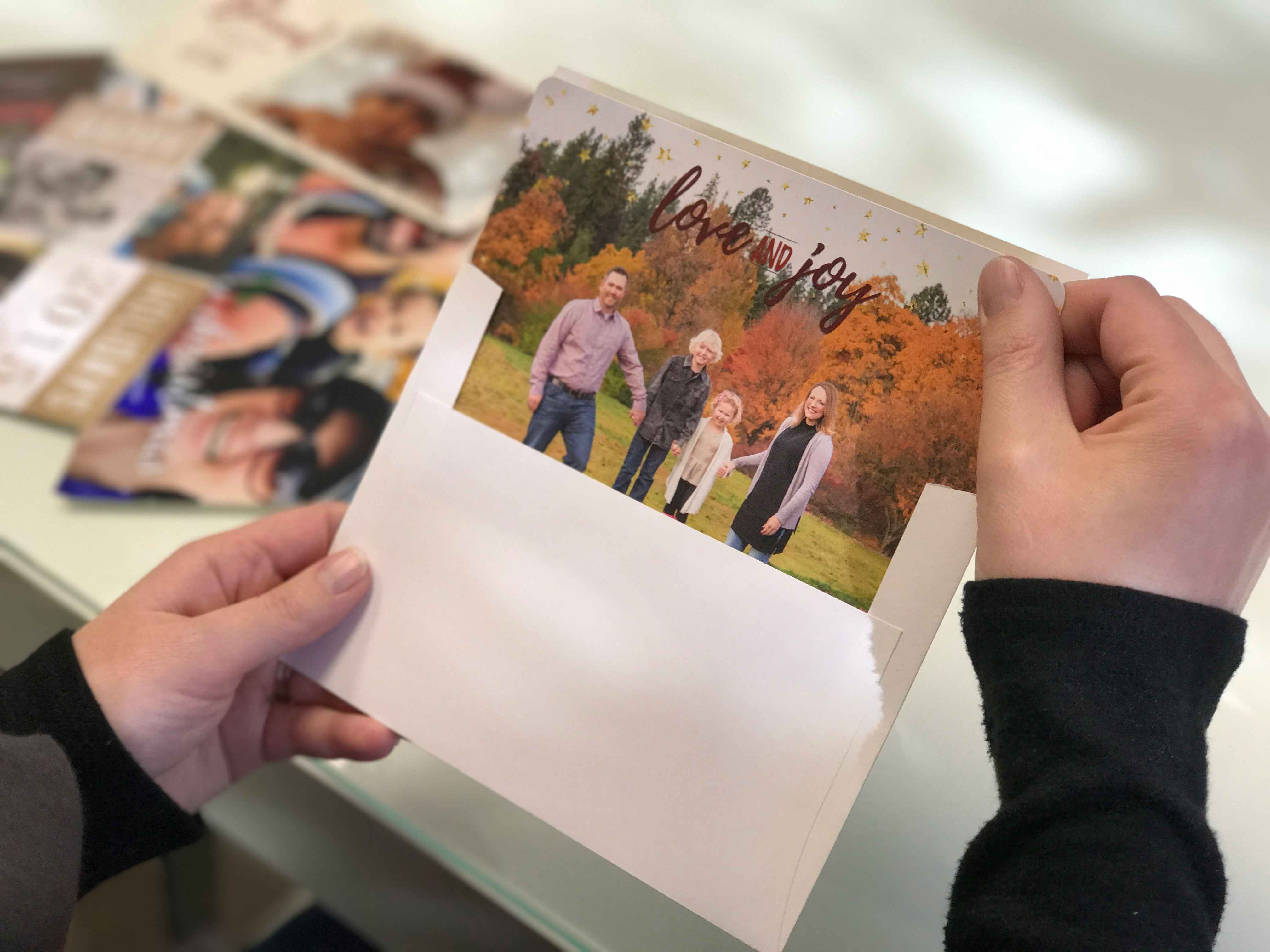 woman pulling holiday family photo card out of envelope