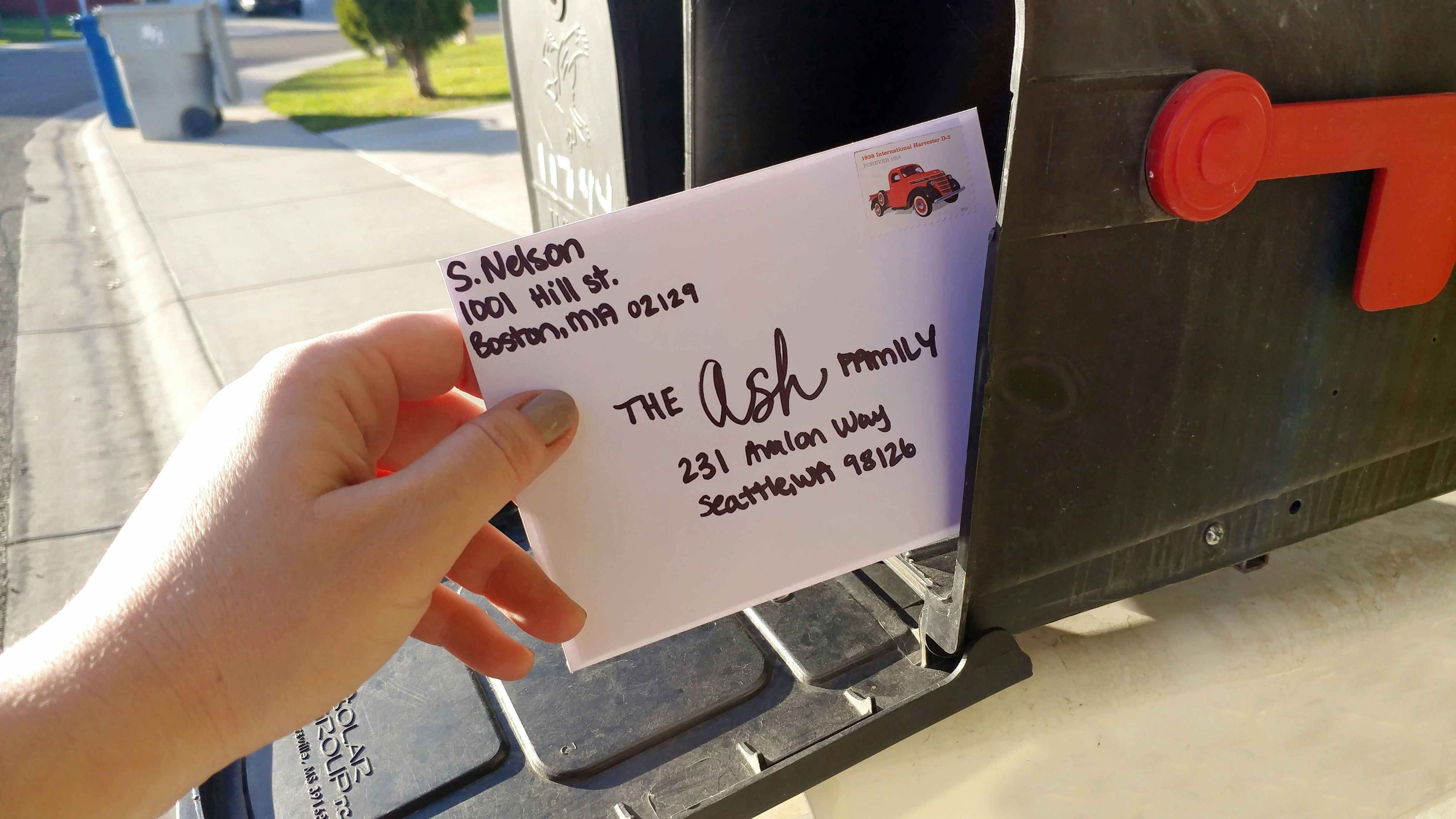 Hand placing a hand written letter into a mailbox