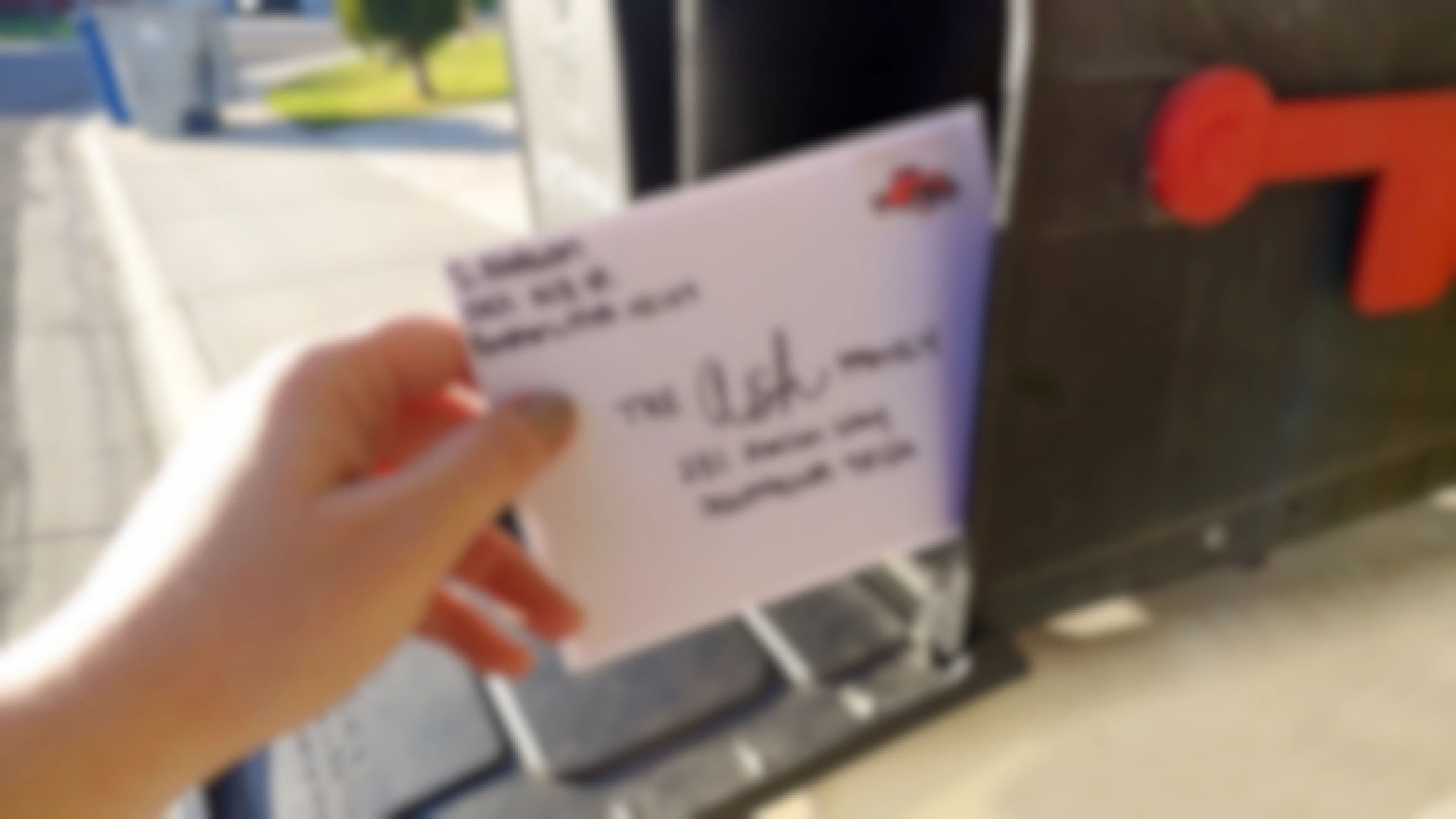 Hand placing a hand written letter into a mailbox