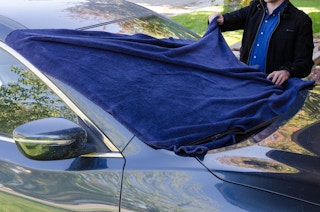 A person putting a blanket over a car window. 