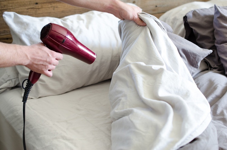 A person blow drying their sheets.