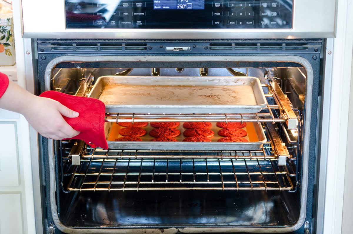 a person taking a pan of cookies out of the oven.