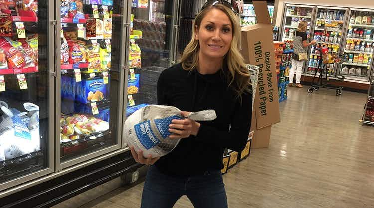 woman smiles holding a free turkey at store