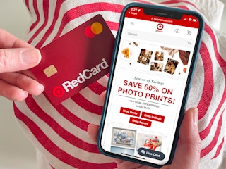 Someone looking at the Target Photo site on a cell phone and holding a Red Card