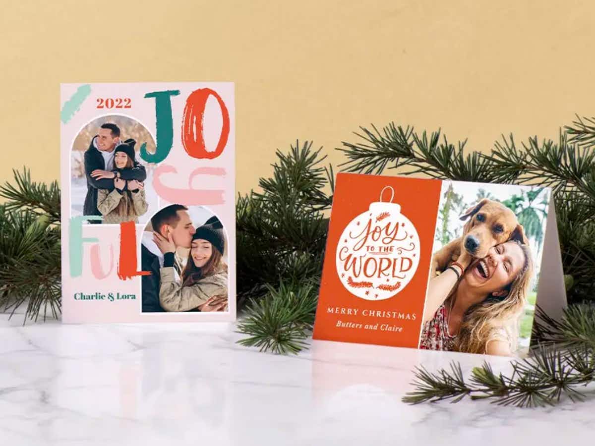Some holiday photo cards from Zazzle on a mantel with pine garland