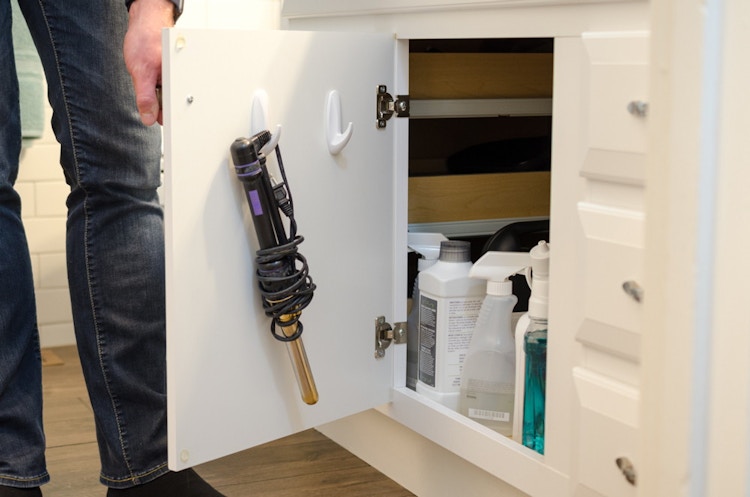 A person opening a cupboard in a bathroom