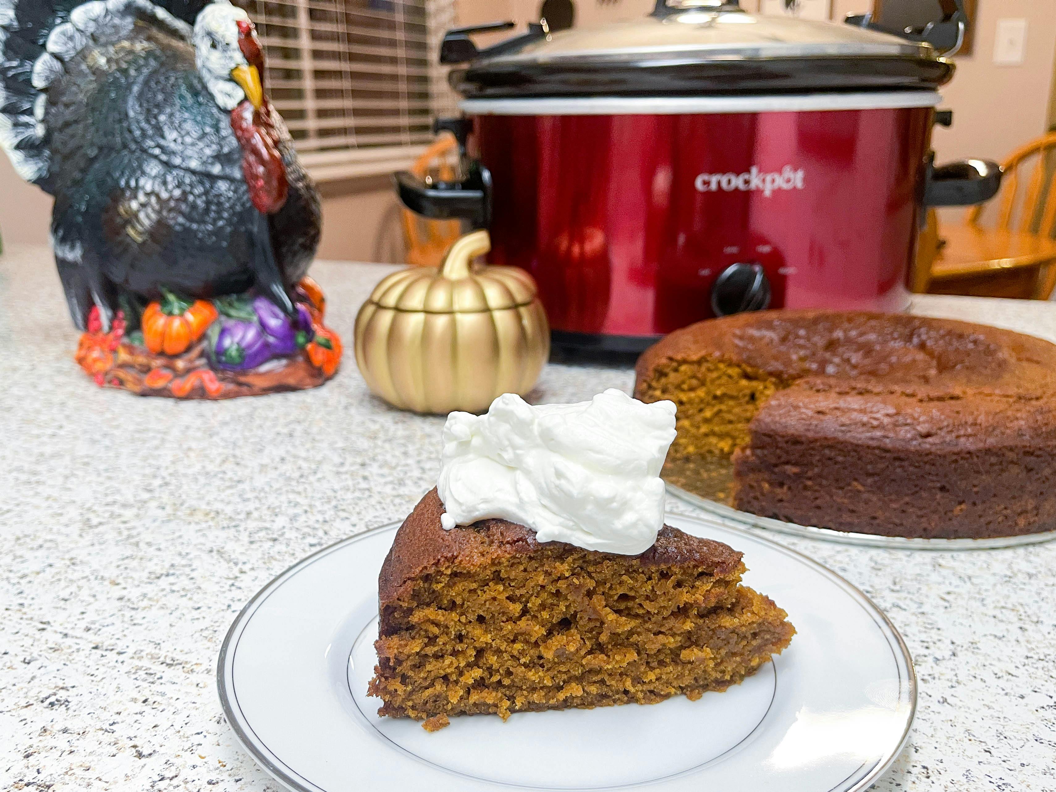 A slice of pumpkin cake on a plate in front of a crock pot