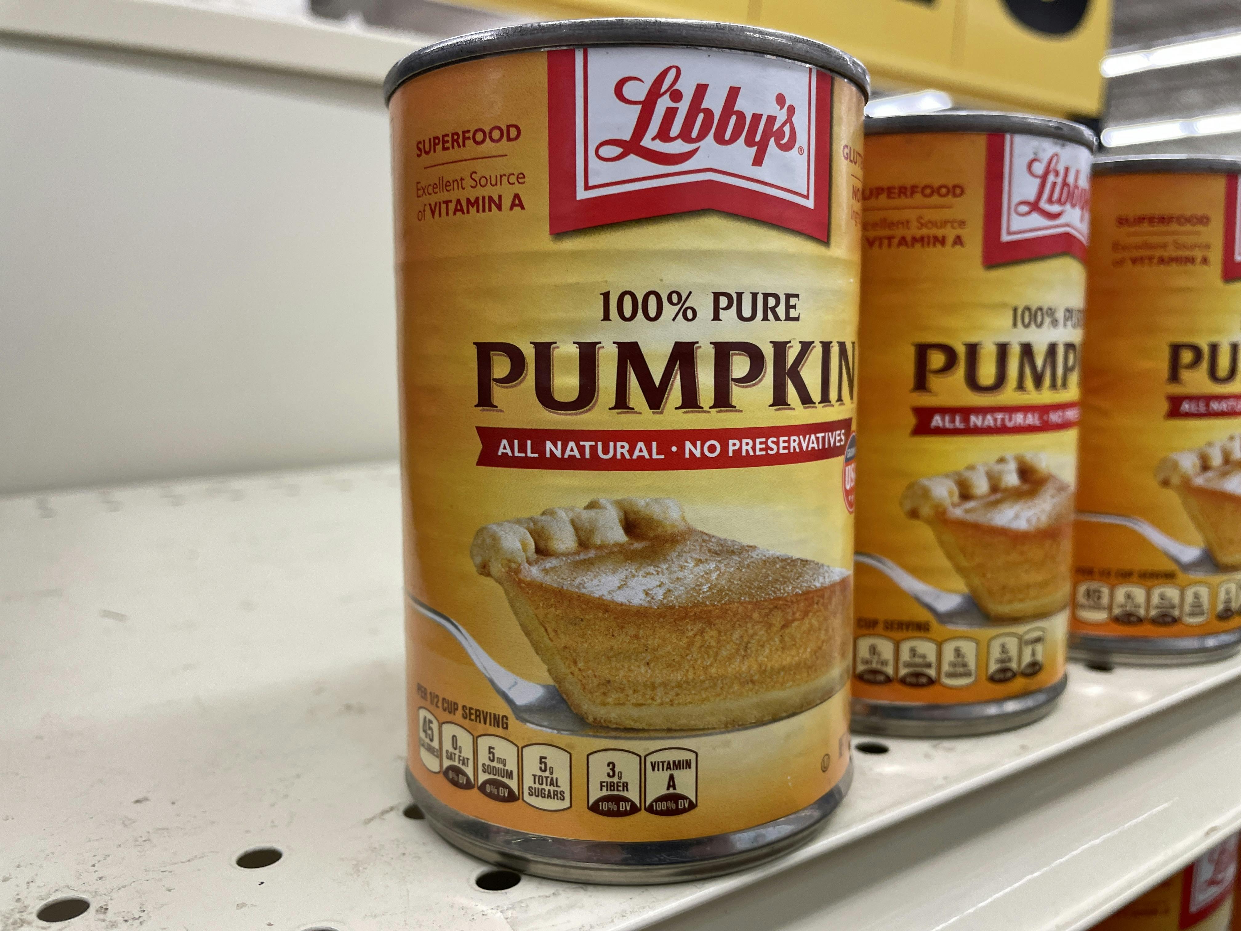 Three cans of Libby's canned pumpkin on a store shelf.