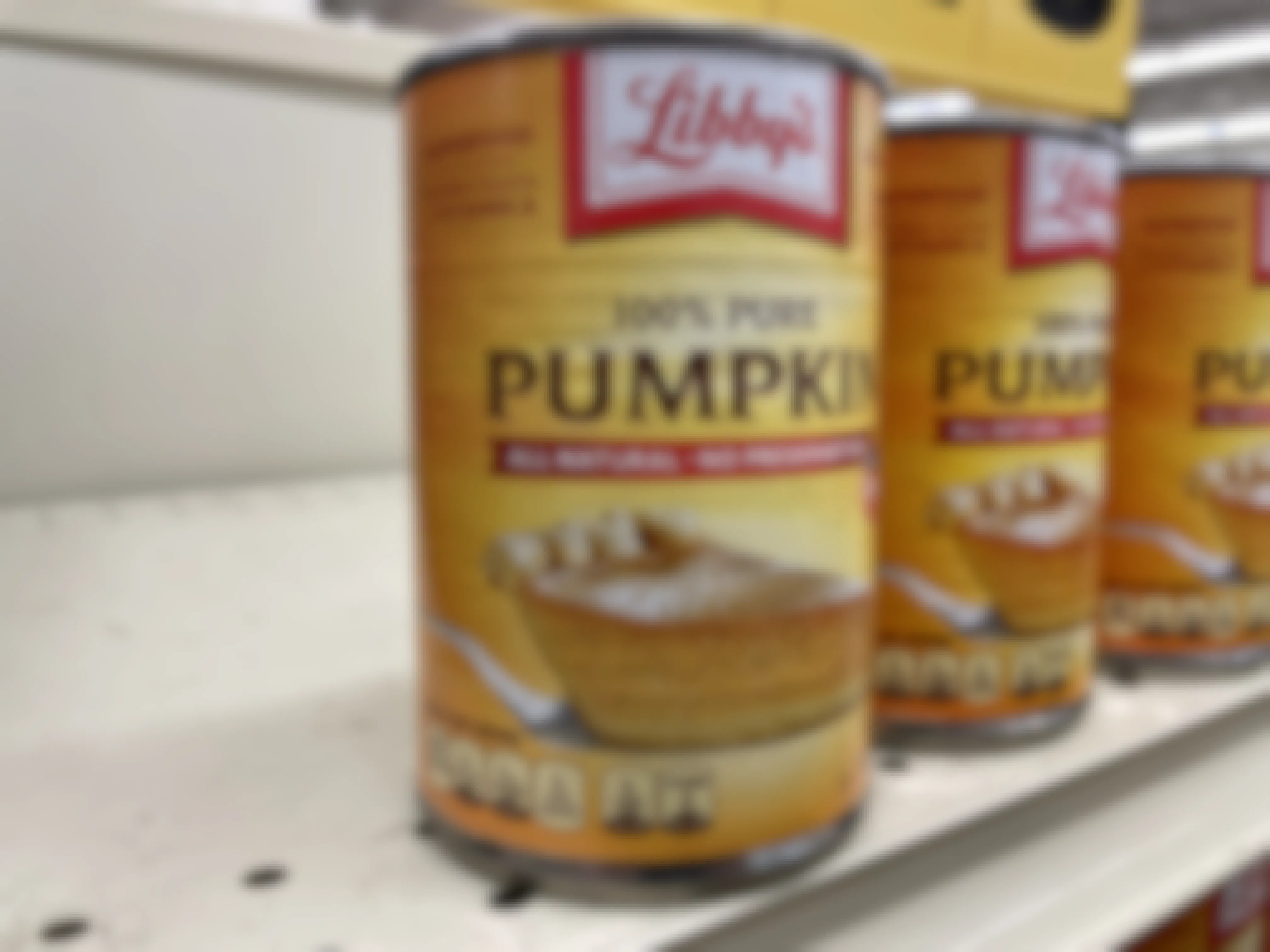 Three cans of Libby's canned pumpkin on a store shelf.