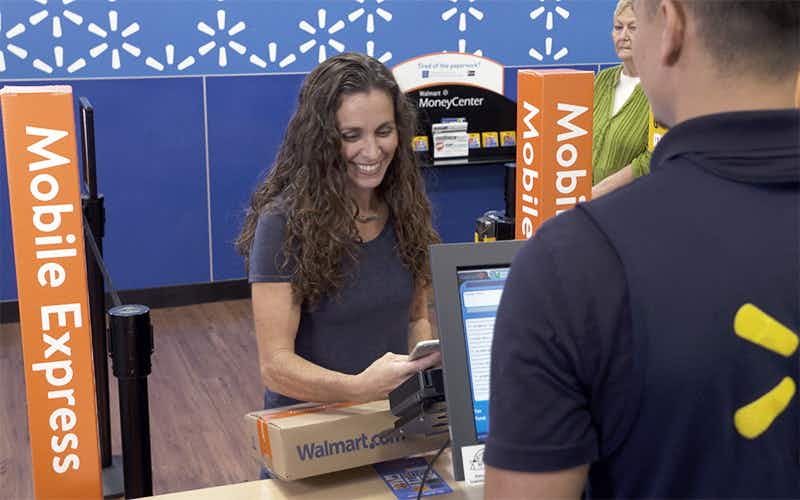 Woman behind the counter at Walmart customer service with a sign that says mobile express