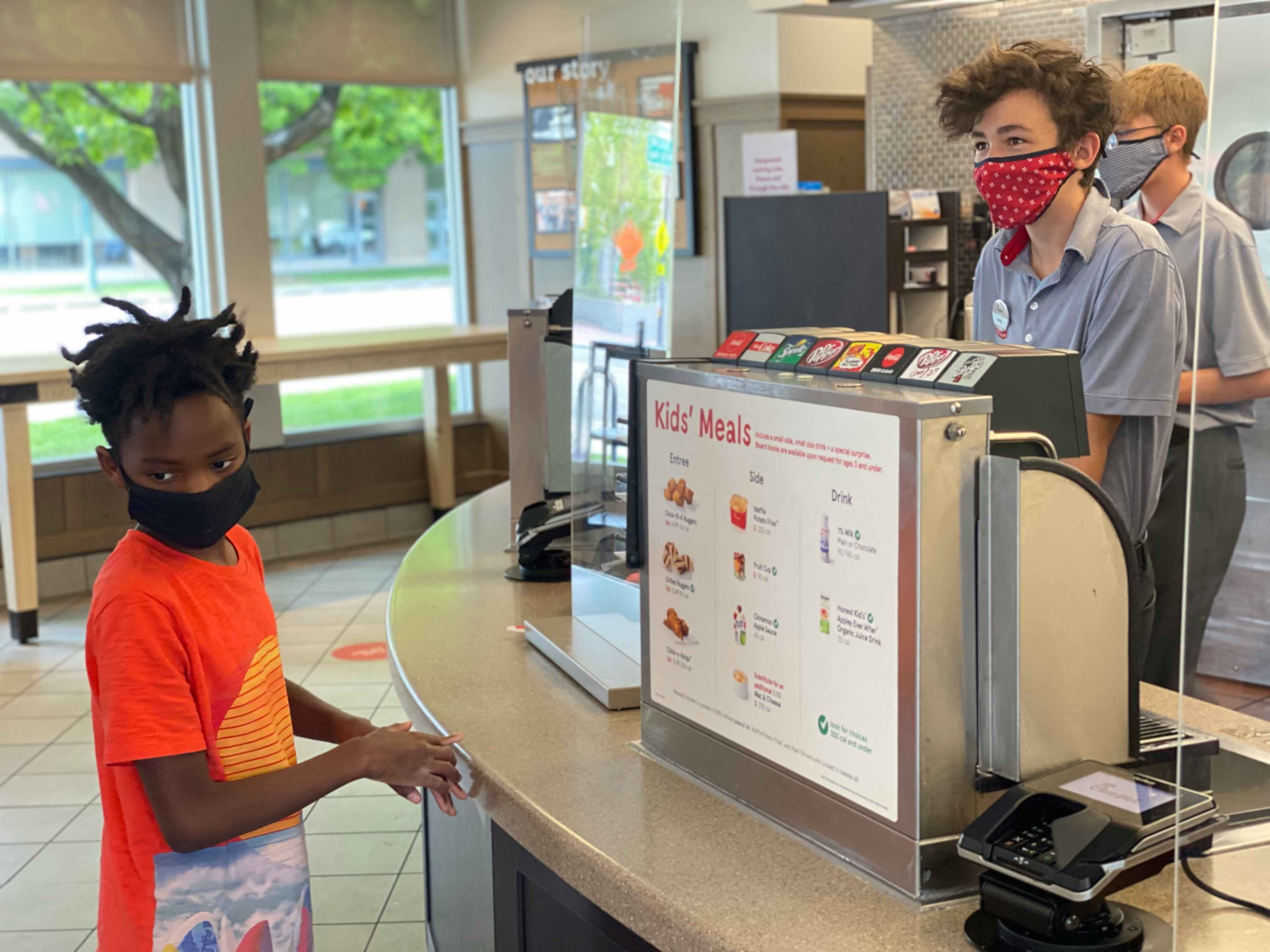 A boy standing at a Chick-fil-A counter with employees behind it.