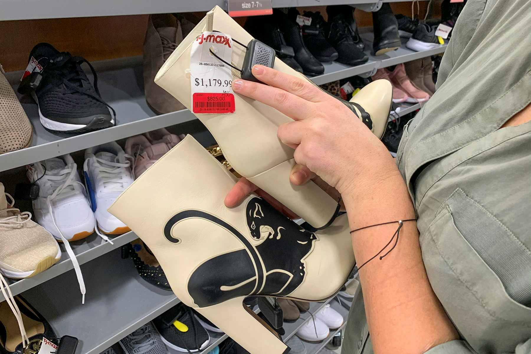 A woman holding Valentino boots with a red clearance sticker on them.