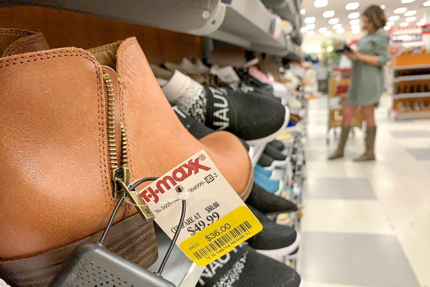 A pair of brown ankle boots with a yellow clearance tag on them.