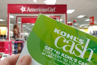 someone holding up Kohls Cash sign in front of American Girl Doll sign
