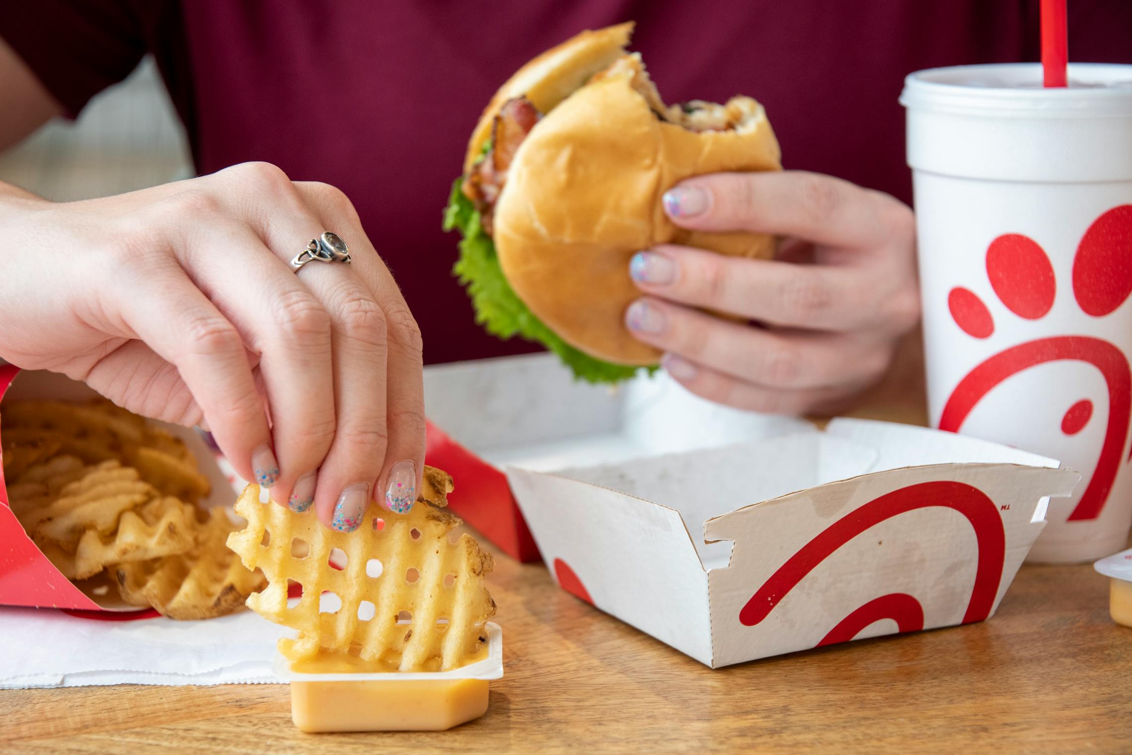 chick-fil-a vs. mcdonalds - A person eating a Chick-fil-A meal while sitting at a table.