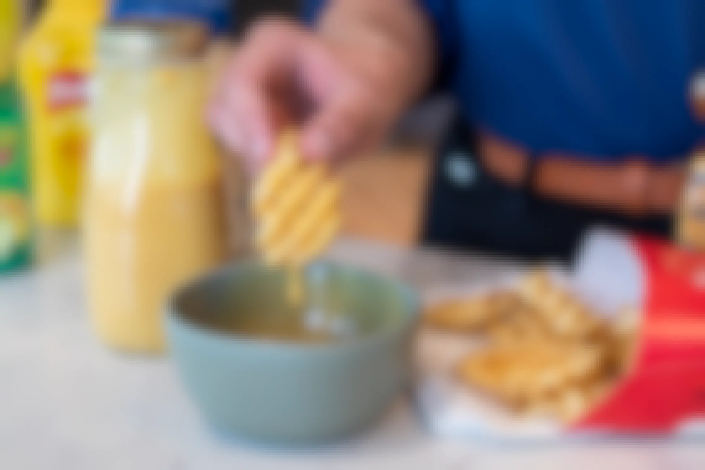 Homemade chick-fil-a sauce being poured from a glass bottle into a bowl.