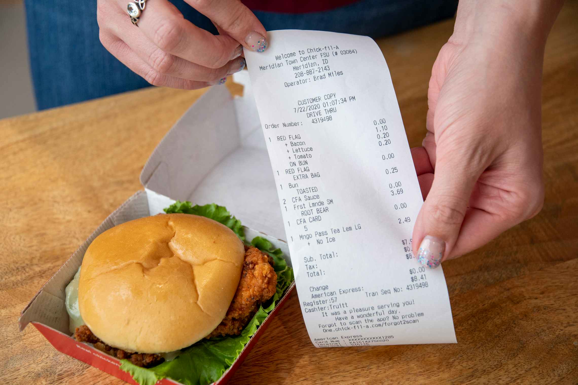 A person holding a receipt next to a Chick-fil-a chicken sandwich. 