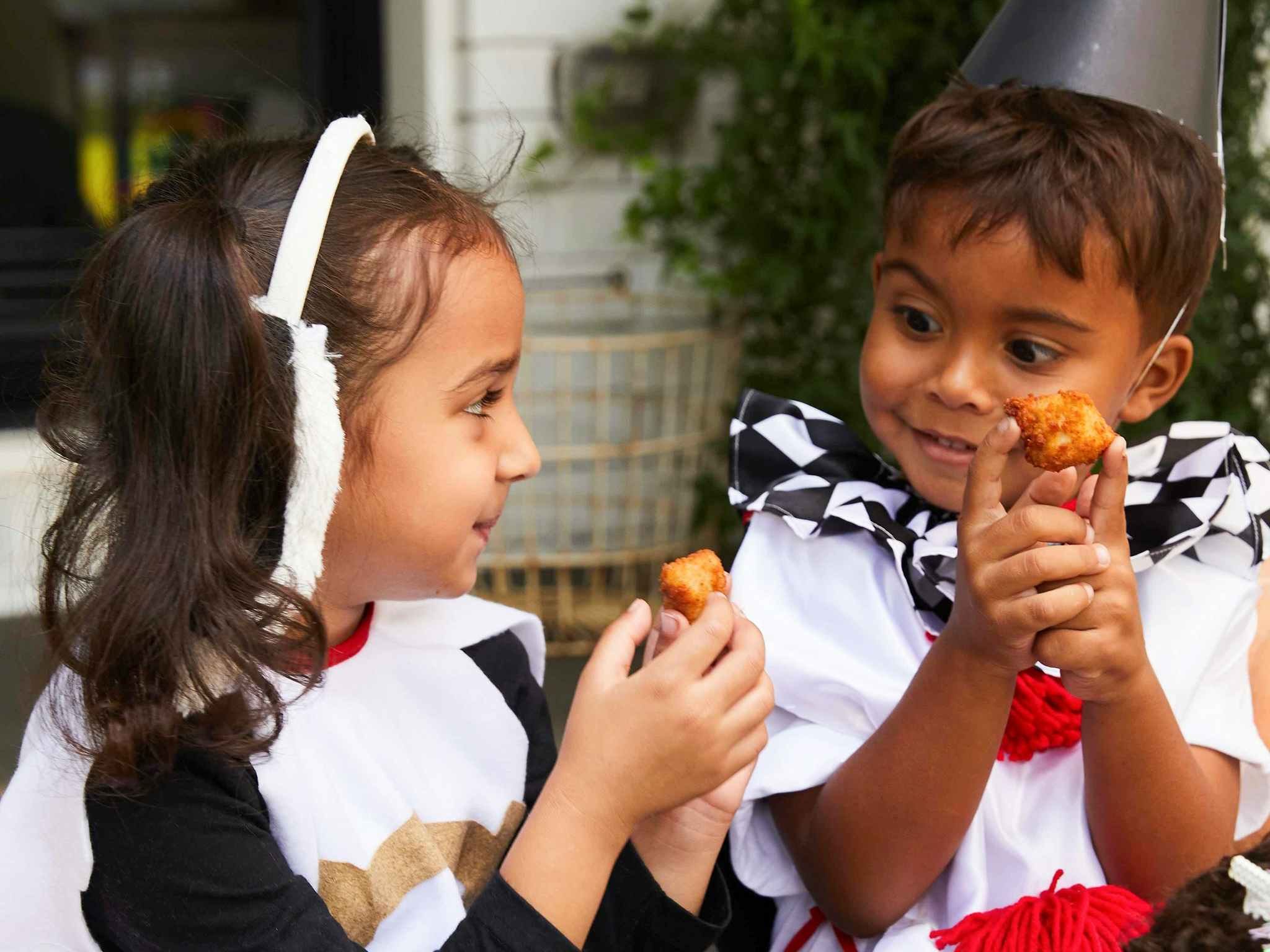 Two children dressed up eating Chick-Fil-A Chicken nuggets