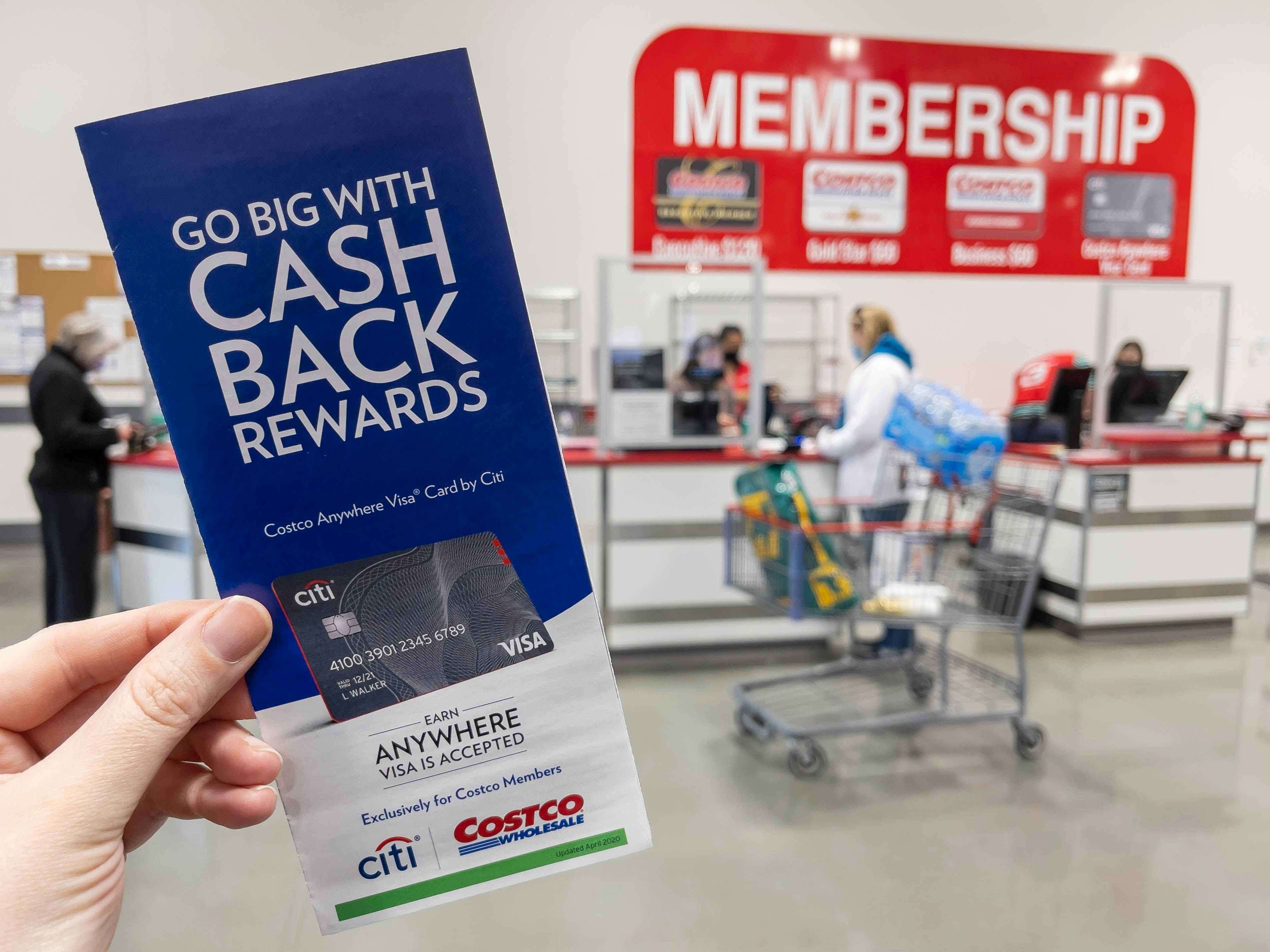 A person holding a pamphlet for information on a Costco Credit card