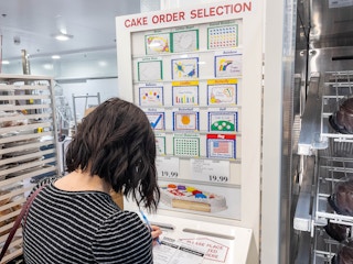 A woman filling out a form to order a half sheet cake in the Costco bakery