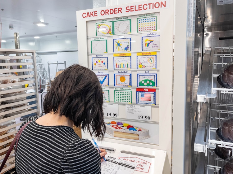 A woman filling out a form to order a half sheet cake in the Costco bakery