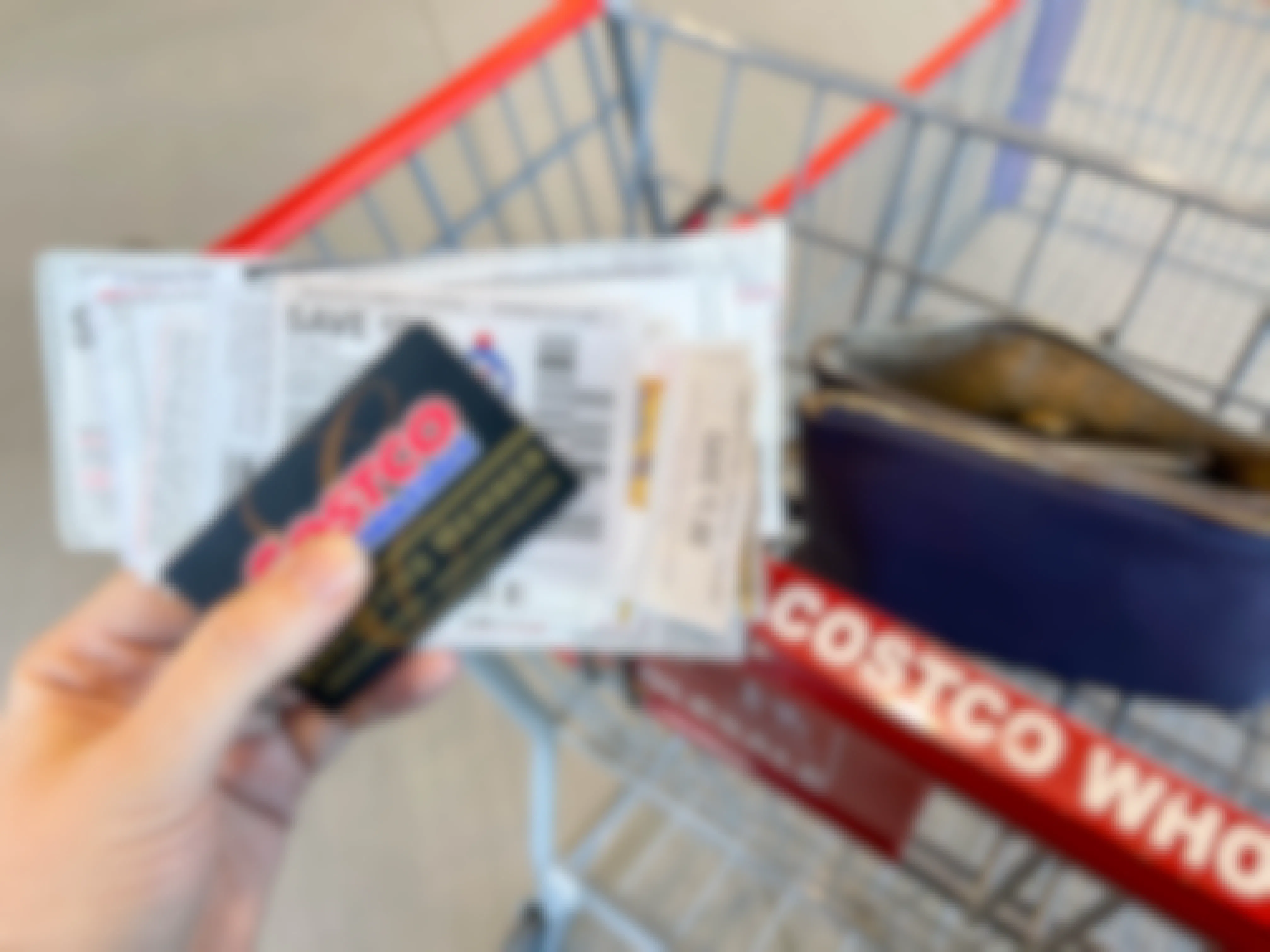 A person holding a costco membership with a stack of coupons