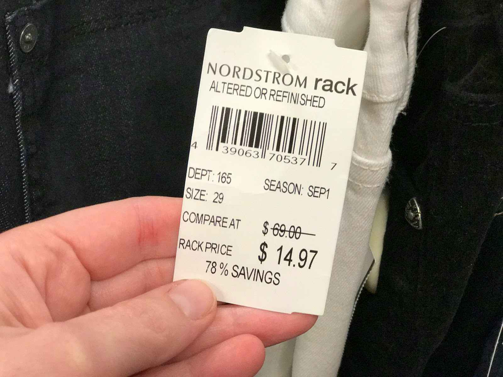 A person holding a price tag that says "Nordstrom Rack Altered or Refinished".