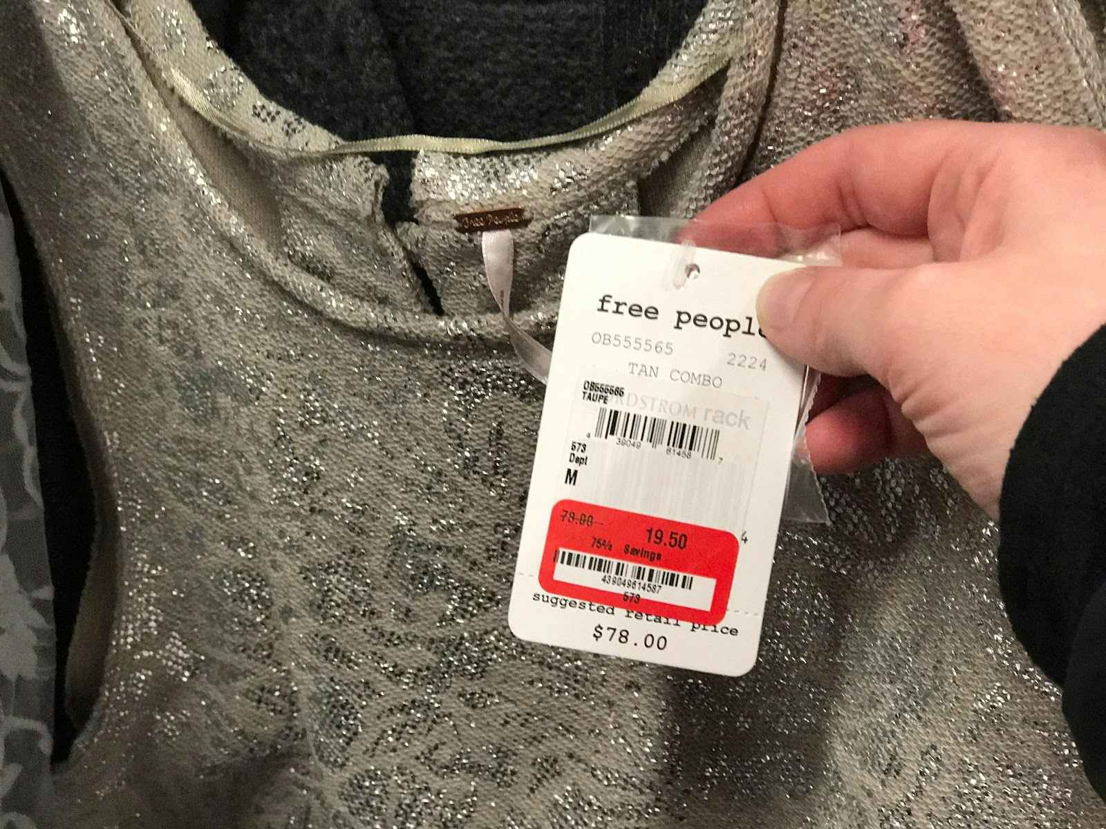 A person holding a price tag that reads "free people" with nordstrom rack clearance sticker over it