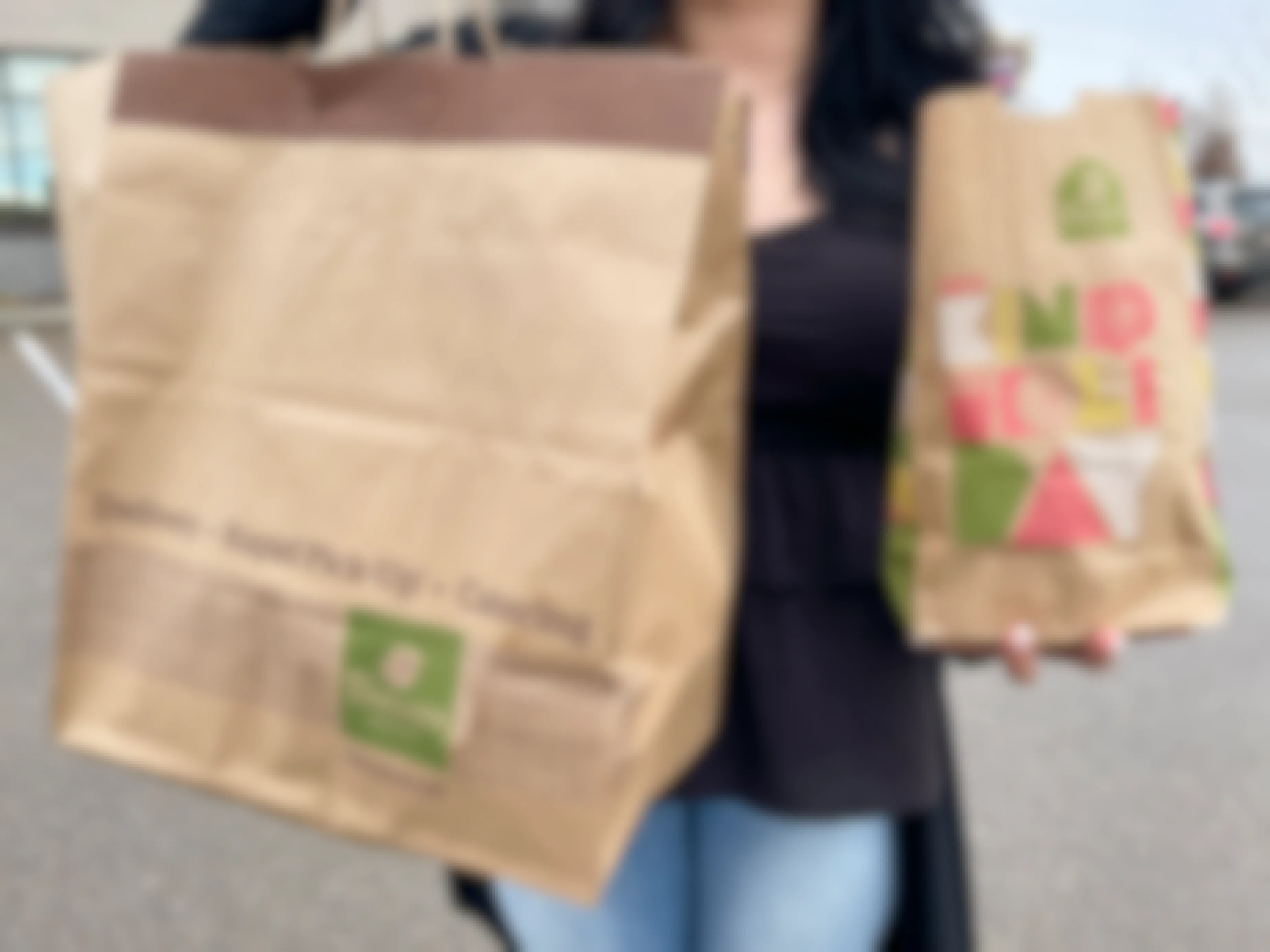 A woman holding two bags of Panera food