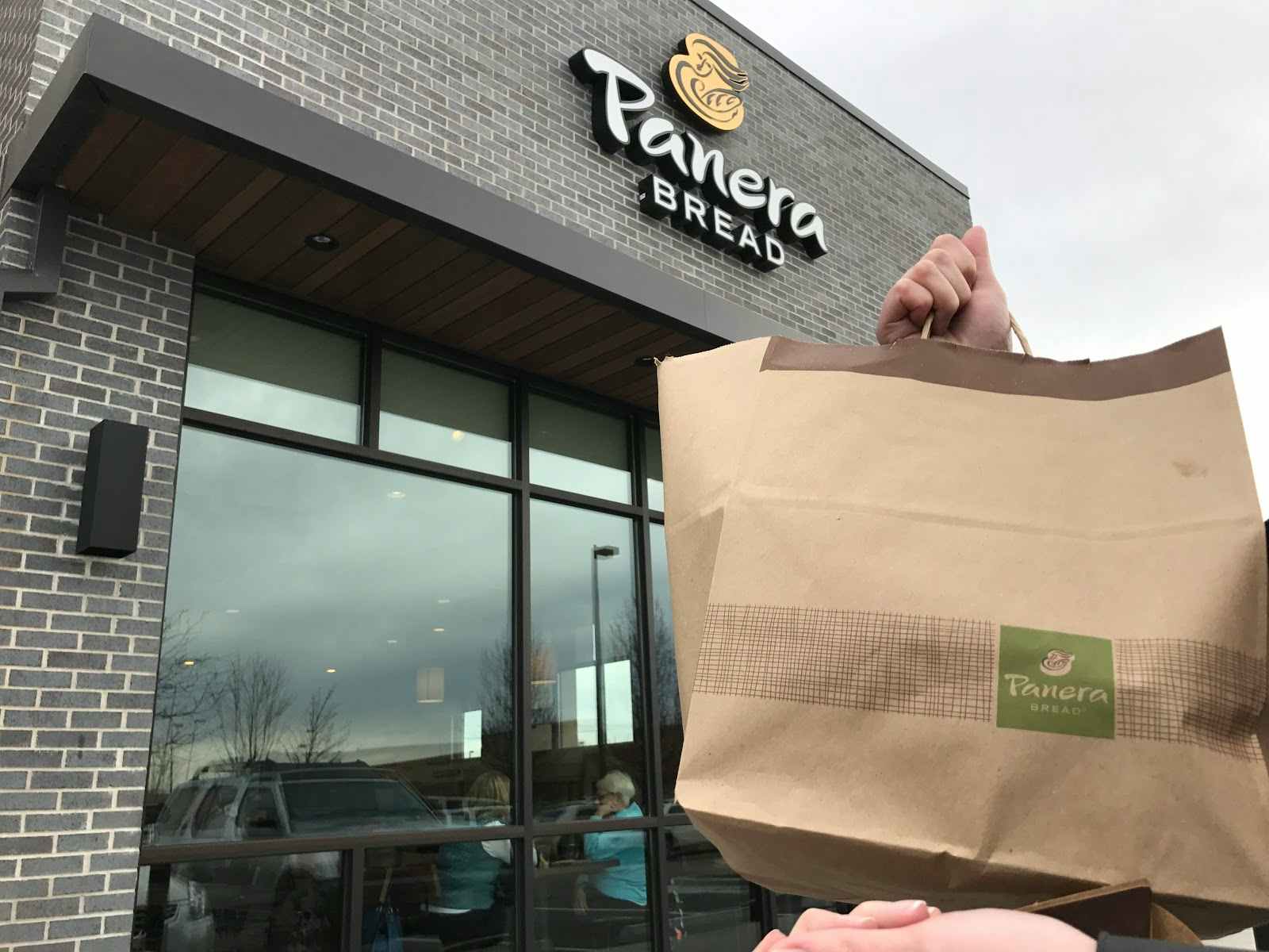 Panera restaurant with a person holding a to-go bag