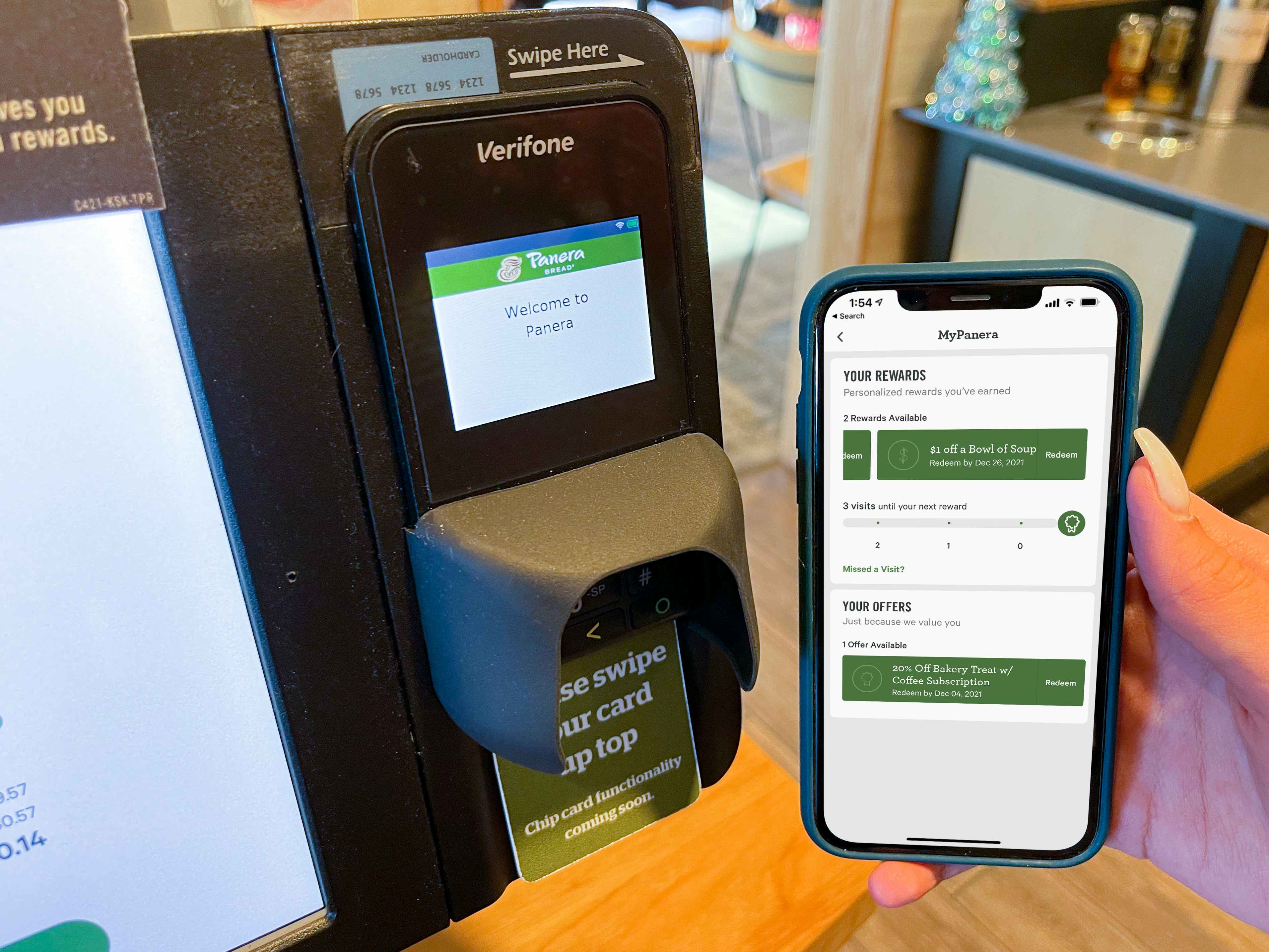 A phone held next to a self checkout kiosk displaying rewards.