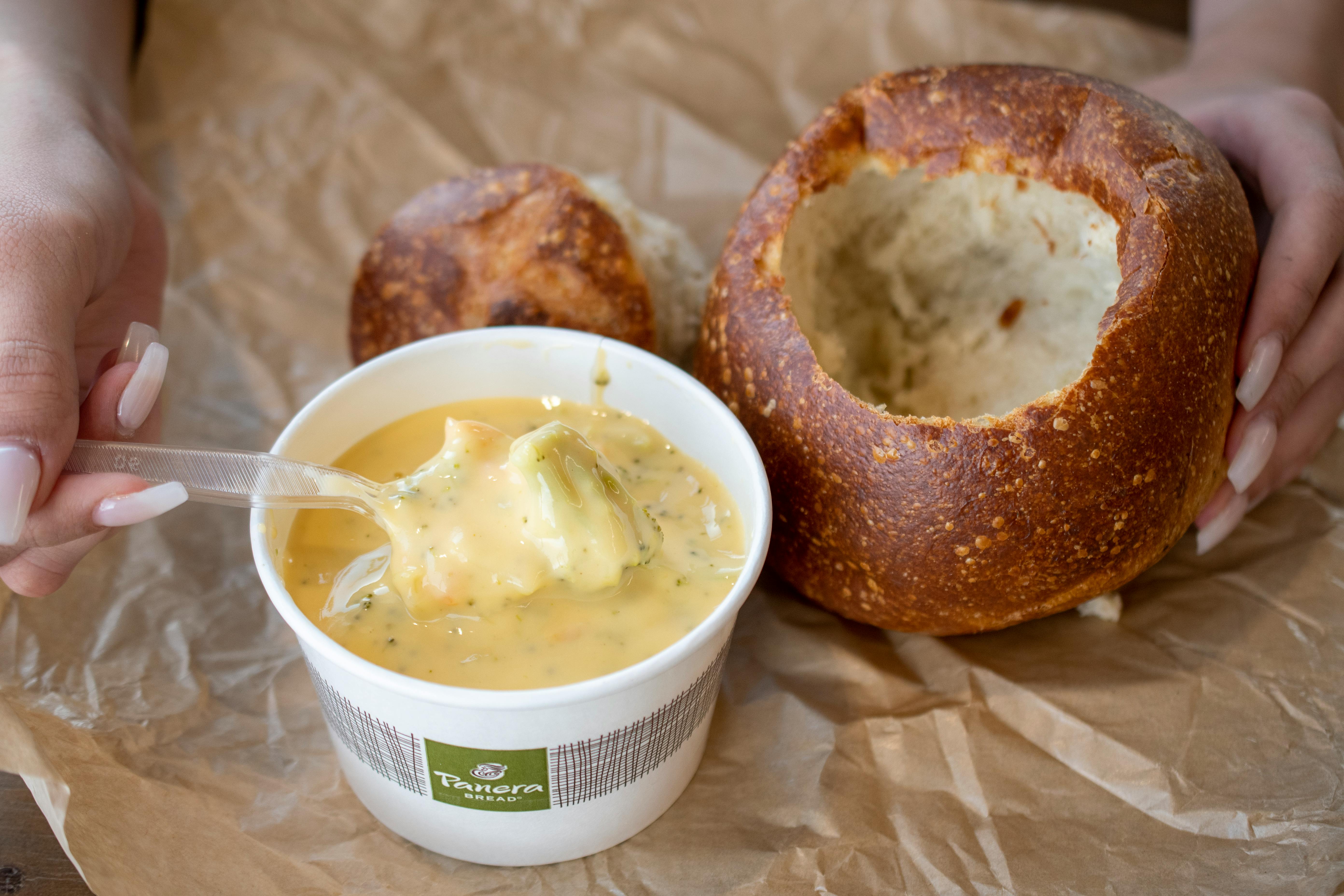 A cup of soup next to a bread bowl