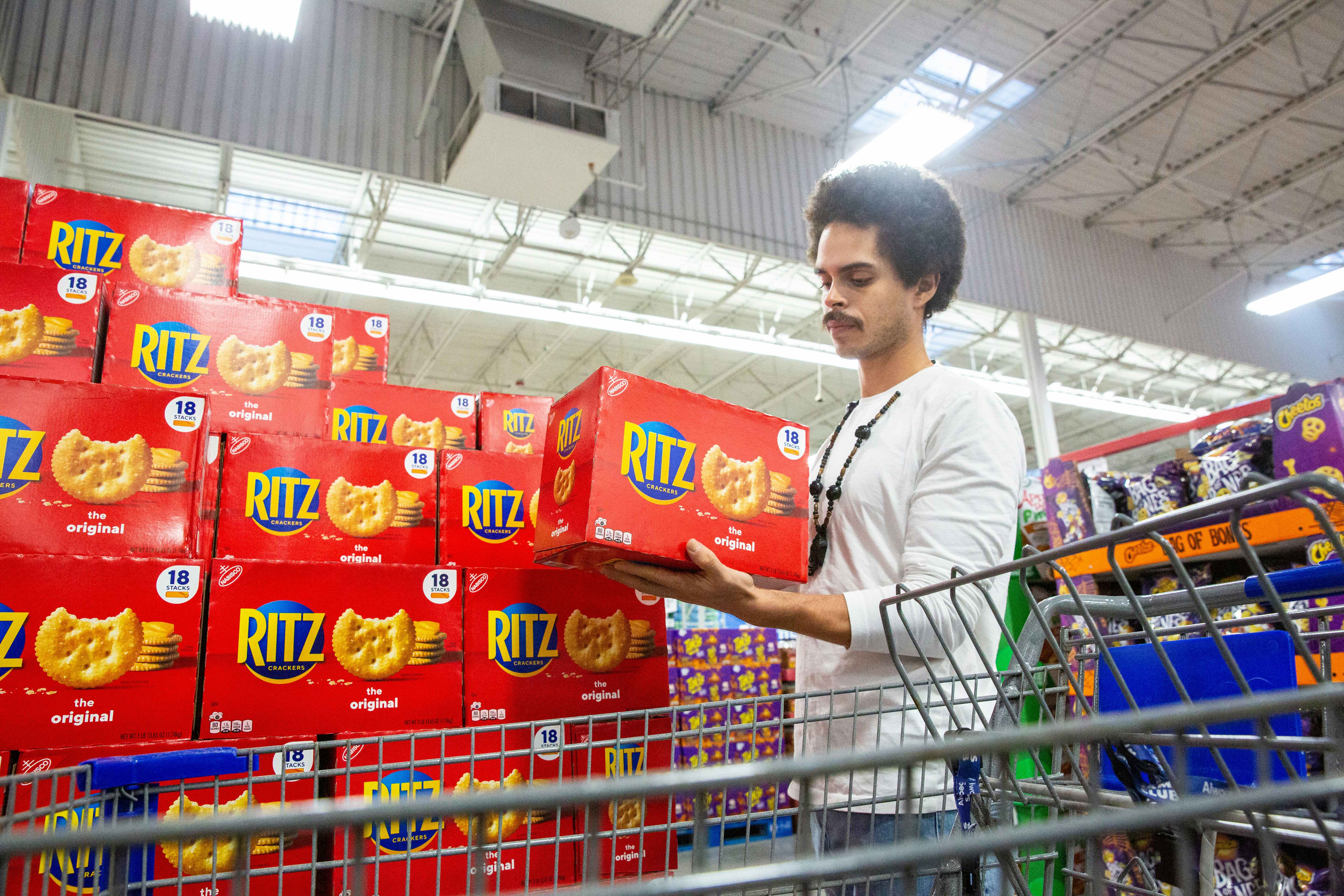 Person picking up a large box of rits crackers inside a Sam's Club 